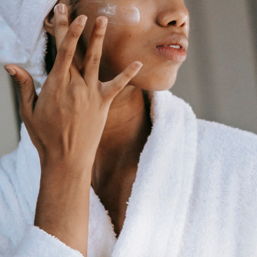 Woman applying moisturizer to her face as part of her skin care routine