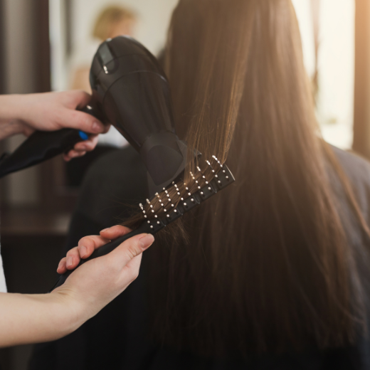Woman styling hair with brush and hair dryer
