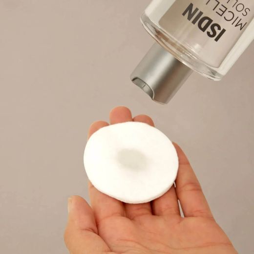ISDIN Micellar Solution being applied to cotton round for makeup removal on the eyebrows