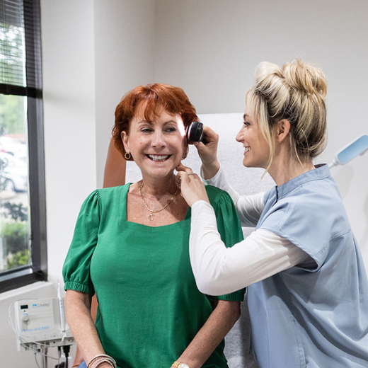 Dr. Amy Wolthoff examining skin of female patient