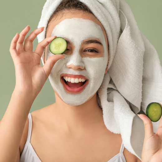 Woman with a skincare face mask holding cucumbers up to her eyes