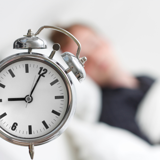 Clock next to a bed to symbolize a good night sleep