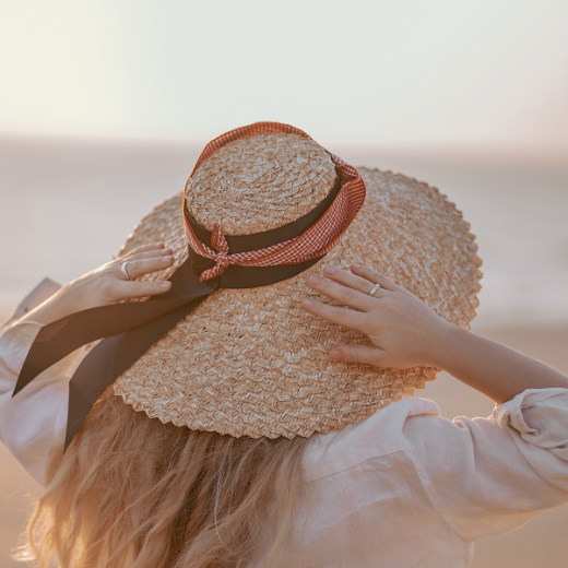 Woman on beach wearing a wide brimmed hat for sun protection