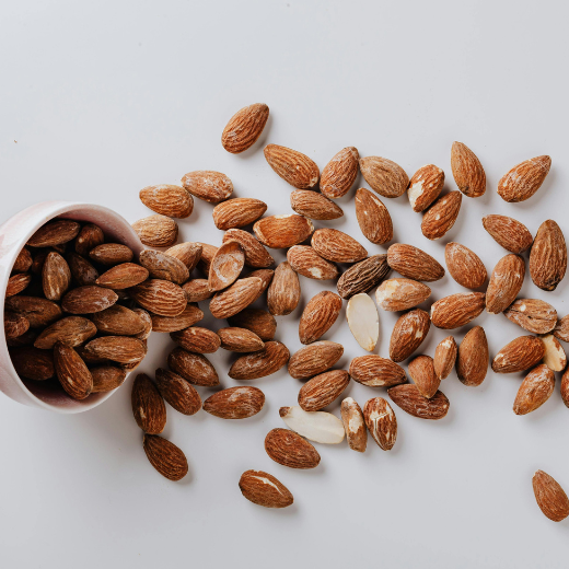 Almonds spilled from a bowl, providing nutrients for hyaluronic acid production