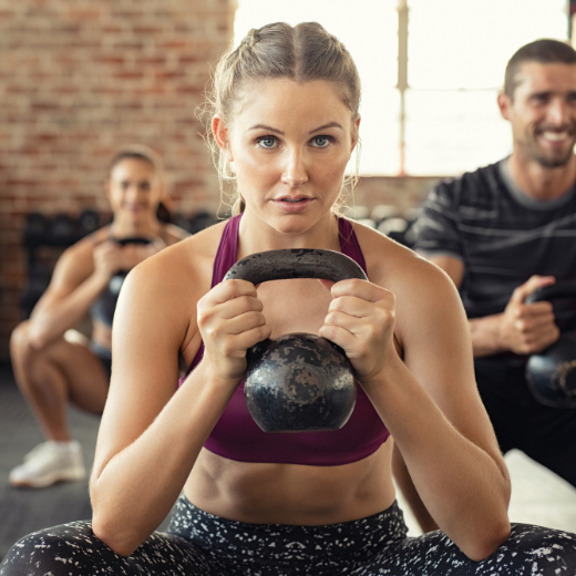 Woman working out with kettle bell during a group fitness class